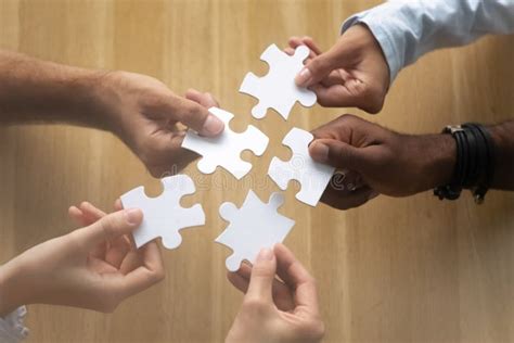 Hands Of Diverse Team Members Assembling Jigsaw Puzzle Close Up Stock