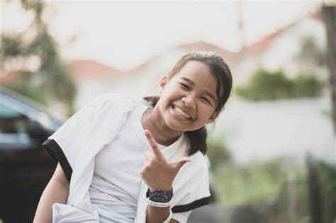 Premium Photo Portrait Of Smiling Girl Gesturing While Sitting Outdoors