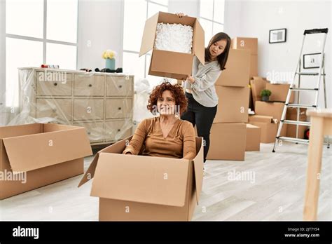 Mature Mother And Down Syndrome Daughter Moving To A New Home Having Fun Inside Box Stock Photo