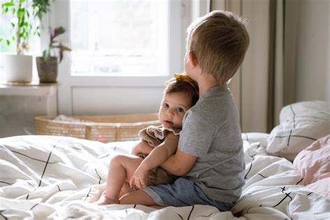 Premium Photo Cute Brother Sitting With Sister On Bed