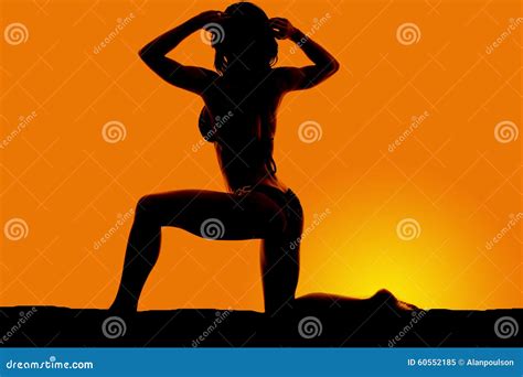 Silhouette Of A Woman In A Bikini On A Knee With Two Hands In Ha Stock