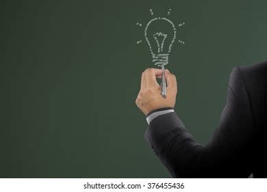 Businessman Drawing Light Bulb On Board Stock Photo