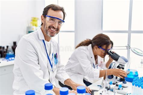 Middle Age Man And Woman Partners Wearing Scientist Uniform Using