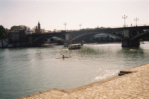 Concrete Bridge With Arches Over A Lake And People On Boats On A Sunny