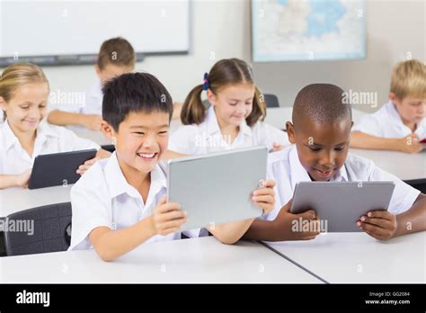 School kids using digital tablet in classroom Stock Photo - Alamy