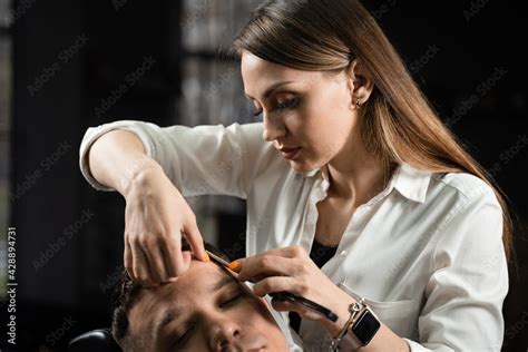 Straight razor cut man hair in barbershop. Attractive woman barber ...