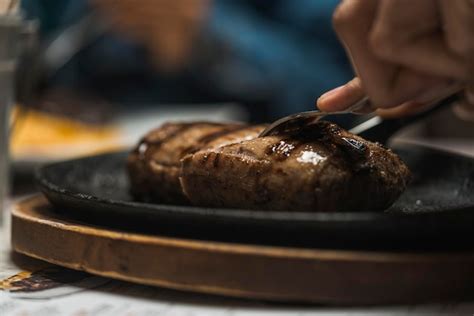 Primer Plano De Una Persona Cortando Un Trozo De Carne Asada En Un