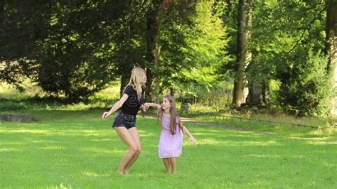 Mother And Daughter Jumping And Holding Hands In The Park Stock Video