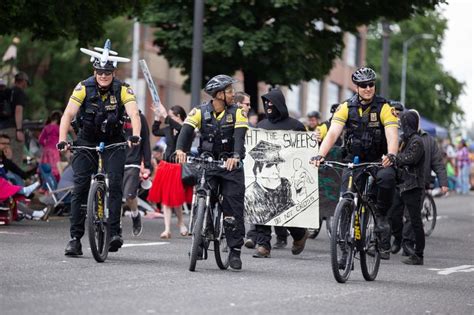 Police Officers On Bicycles Riding Along Side Anti Cop Masked