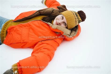 Young woman in orange jacket laying on the ground after a freshの写真素材