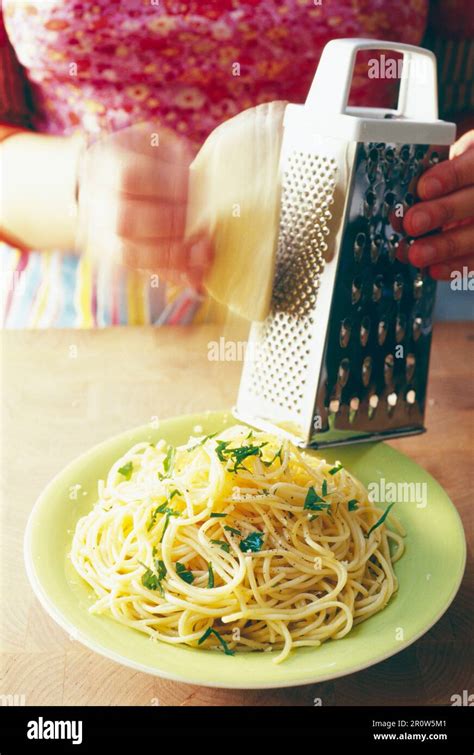 Grating cheese on a plate of spaghetti Stock Photo - Alamy