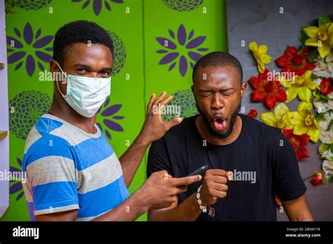 Young Black Man Wearing A Nose Mask To Prevent Himself From A Pandemic And Using His Phone Stock