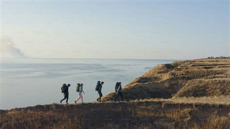 The four tourists walking on the rocky coastline photo – Hiking group