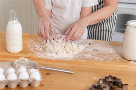 Premium Photo A Woman And A Man Are Kneading Dough On A Table