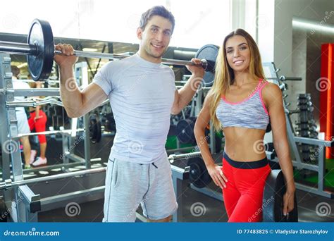 Athletic Man And Woman With Barbell Doing Exercises In The Gym Stock