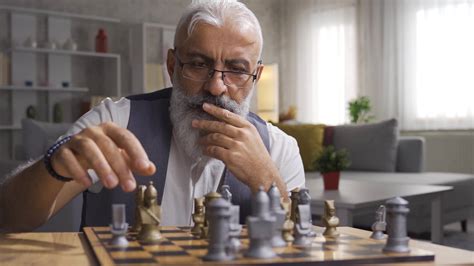 Mature man playing chess and developing his strategies. Thoughtful man