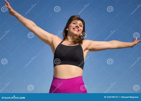 Mature Woman In Sportswear Jumping In The Air Happy In An Outdoor Park