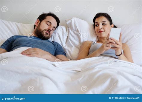 Cheating Wife Using Mobile Phone Lying In Bed Next To His Sleeping