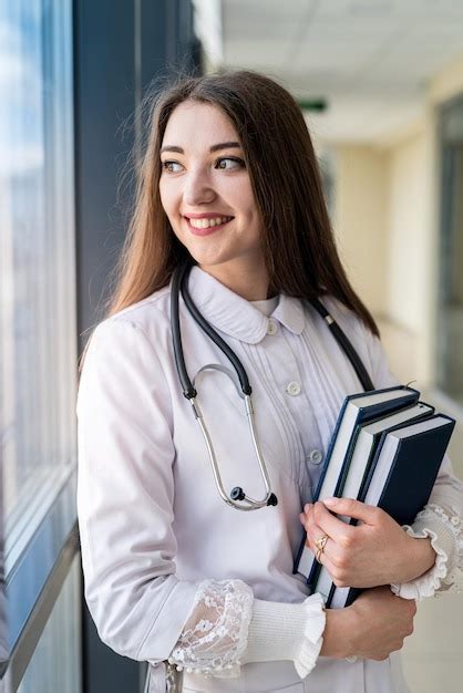 Sonriente Joven Doctora En Uniforme Con Estetoscopio Sosteniendo Libro