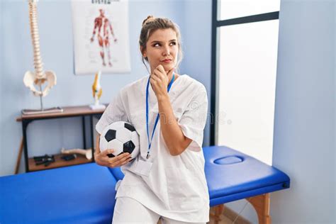 Young Woman Working At Football Therapy Clinic Serious Face Thinking