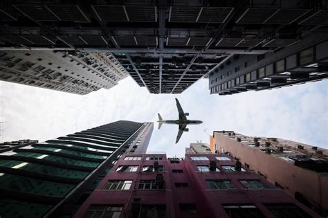 Premium Photo Airplane Flying Over Buildings Against Sky