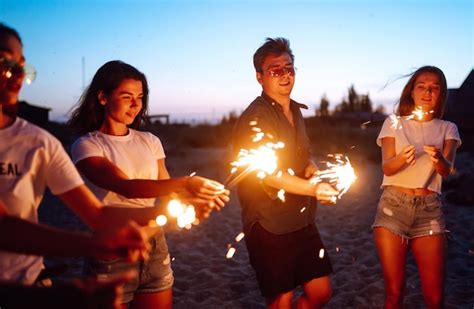 Premium Photo Group Of Friends At Night On The Beach With Sparklers