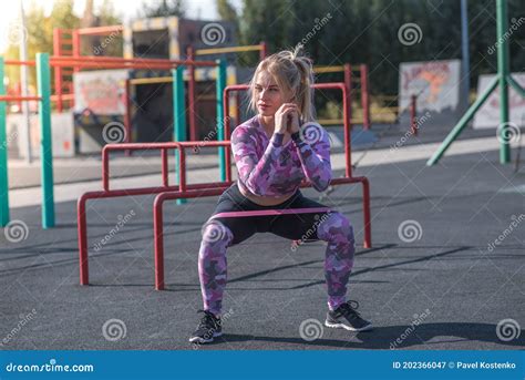 Beautiful And Athletic Blonde Girl Doing Squats On The Street Sports