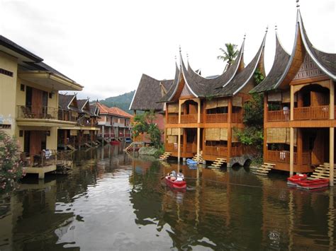 Two Boats Floating Down A River Next To Wooden Buildings