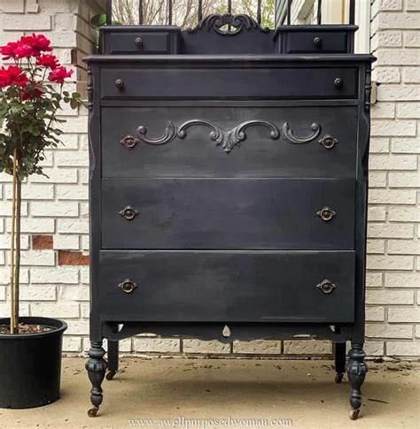 An Old Dresser Is Painted Black And Has Flowers In It