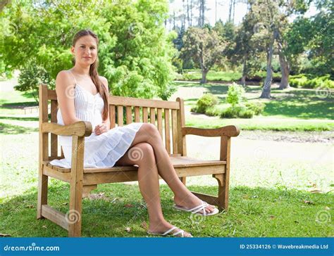 Woman With Her Legs Crossed Sitting On A Park Bench Stock Photo Image