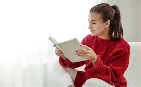 Premium Photo Young Attractive Woman In A Cozy Red Sweater Is Reading