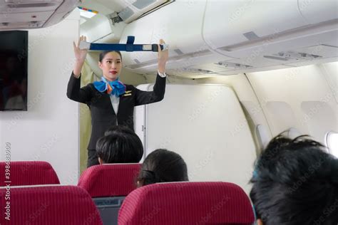 Asian Air Hostess Staff Airline Demonstrate Fasten Seat Belt Safety Procedures To Passengers