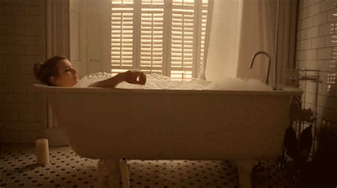 A Woman Laying In A Bathtub Next To A Window