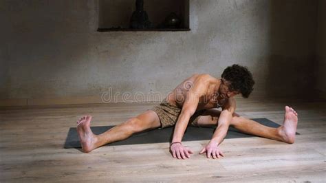 A Man With A Naked Torso Does Fitness Sitting Indoors On A Mat Warm Up Before Training Stock