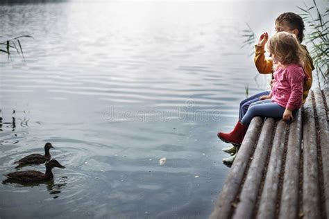 Brother and Sister Sitting on the River Pier and Hugging and Look at ...