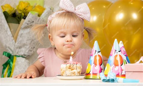 Premium Photo A Twoyearold Girl Blows Out A Candle On A Birthday Cake Makes A Wish