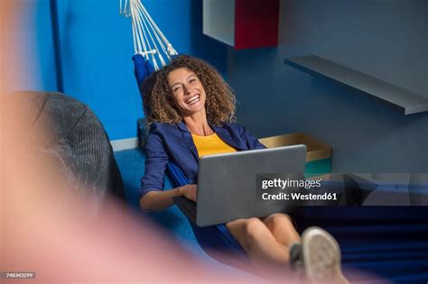 Happy Employee With Laptop Relaxing In Hammock High-Res Stock Photo ...