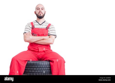 Proud Mechanic Sitting On Top Of Car Wheels With Arms Crossed Looking