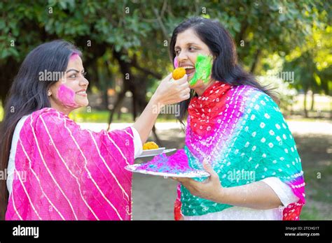 Two Happy Indian Women Wearing White Kurta Celebrating Holi Festival At Park Or Garden While