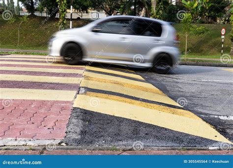 Car Slowing Down At Speed Bump Or Road Hump Painted In Yellow And Black