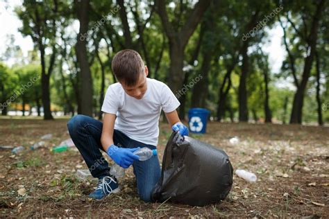 Un Niño Pequeño Recogiendo La Basura Y Poniéndola En Una Bolsa De Basura Negra Sobre Un Fondo