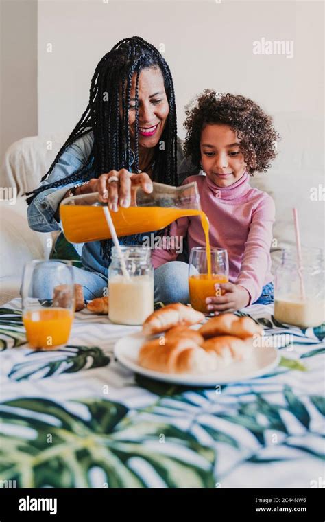 Mère et sa petite fille assises ensemble sur un canapé buvant du jus