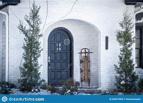 Snow Day Porch Of White Painted Brick House With Arched Front Door