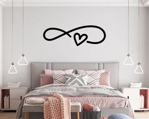 A Bed Room With A Neatly Made Bed And A Wall Decal That Says Love