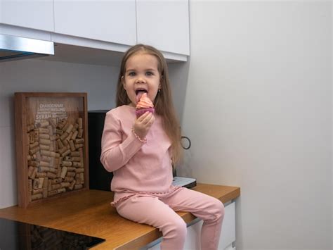 Premium Photo | A little girl is sitting on the kitchen table licking