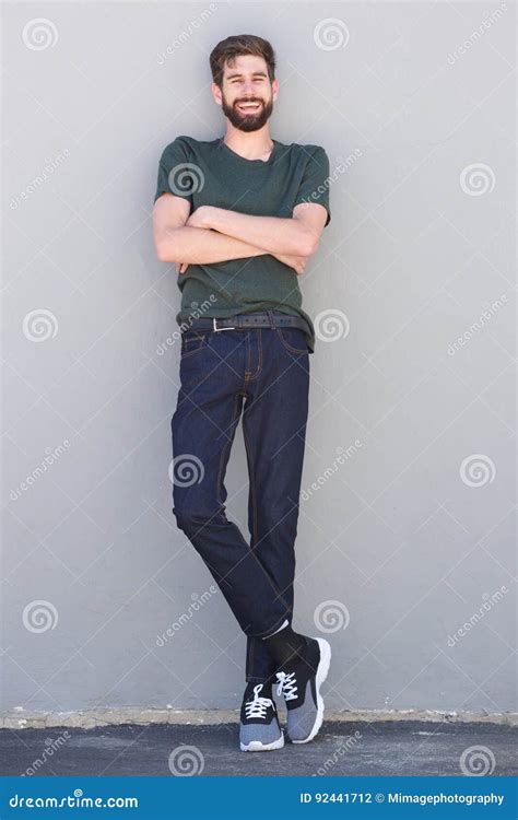 Full Length Laughing Man Standing With Arms Crossed Leaning On Wall