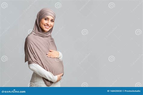 Portrait Of Beautiful Pregnant Muslim Woman In Hijab Over Gray