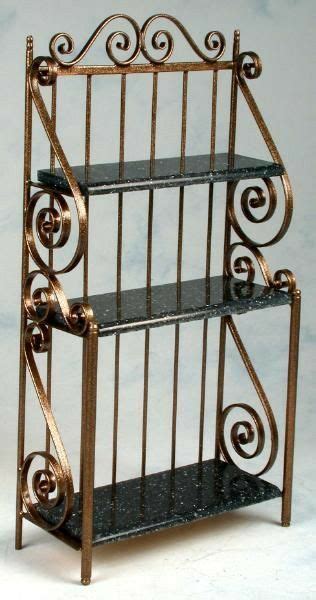 A Three Tiered Metal Shelf With Black Marble Top And Scroll Designs On