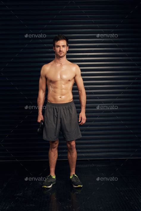 Studio Portrait Of A Shirtless And Well Built Man Standing Against A