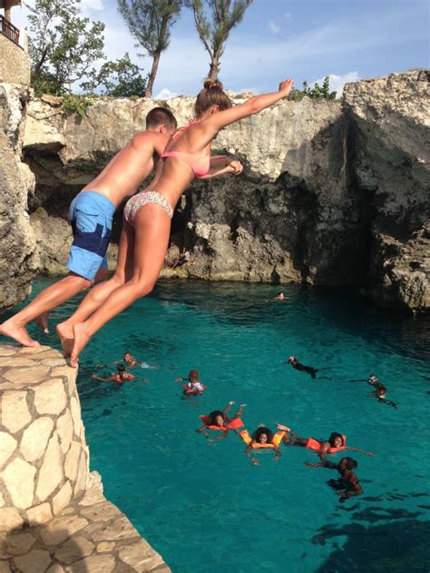 two people jumping into the water from a cliff